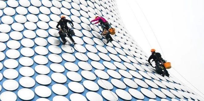 Technicians on rope access, working across a patterned building facade